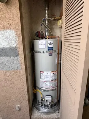 Bradford White water heater in an exterior niche with recirculating pump, drain pan, and earthquake straps