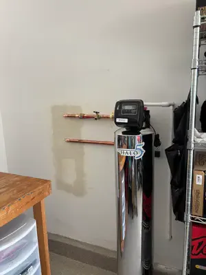 HALO 5 whole-house water filtration tank with chrome finish and copper piping installed in a garage