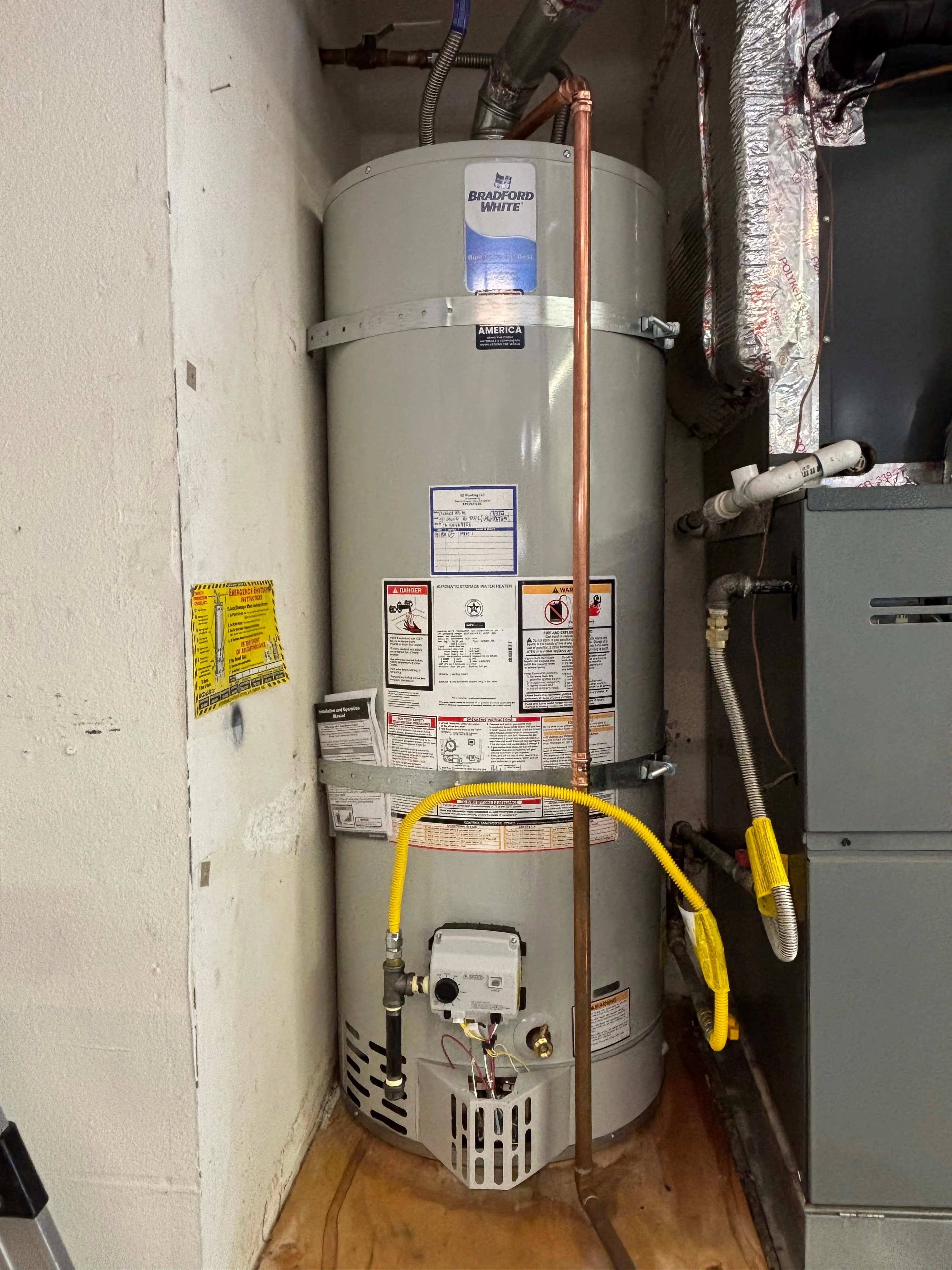 Bradford White tank water heater strapped in a mechanical closet with yellow gas line