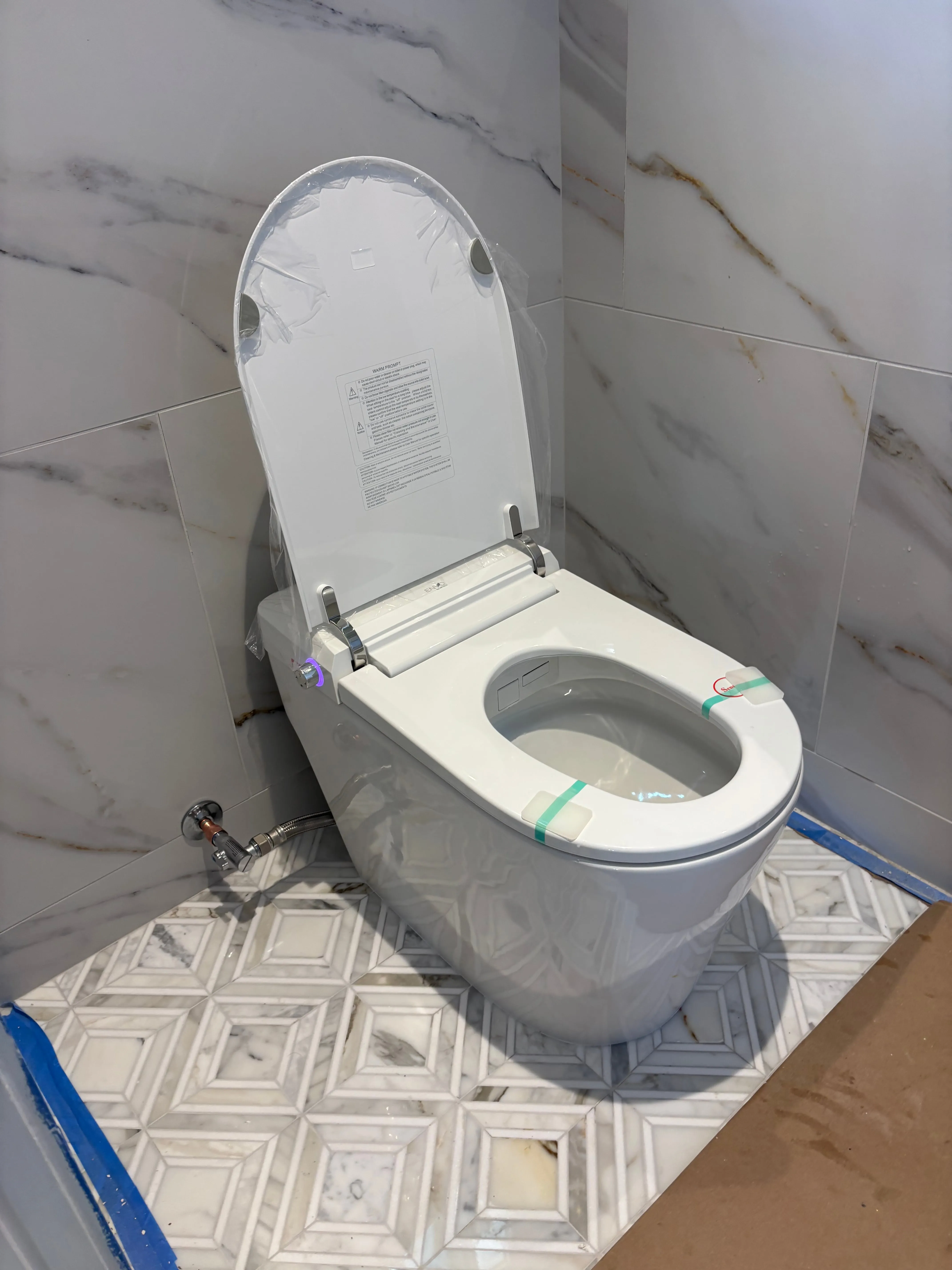 Newly installed white smart toilet against marble-tile walls