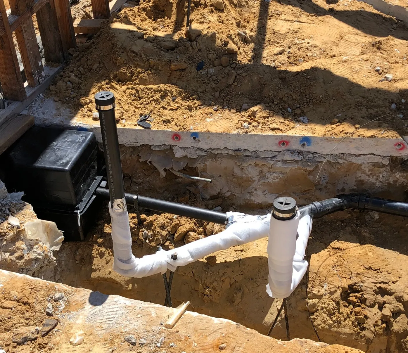 Underground rough-in with black PVC drain and vent lines trenched on site